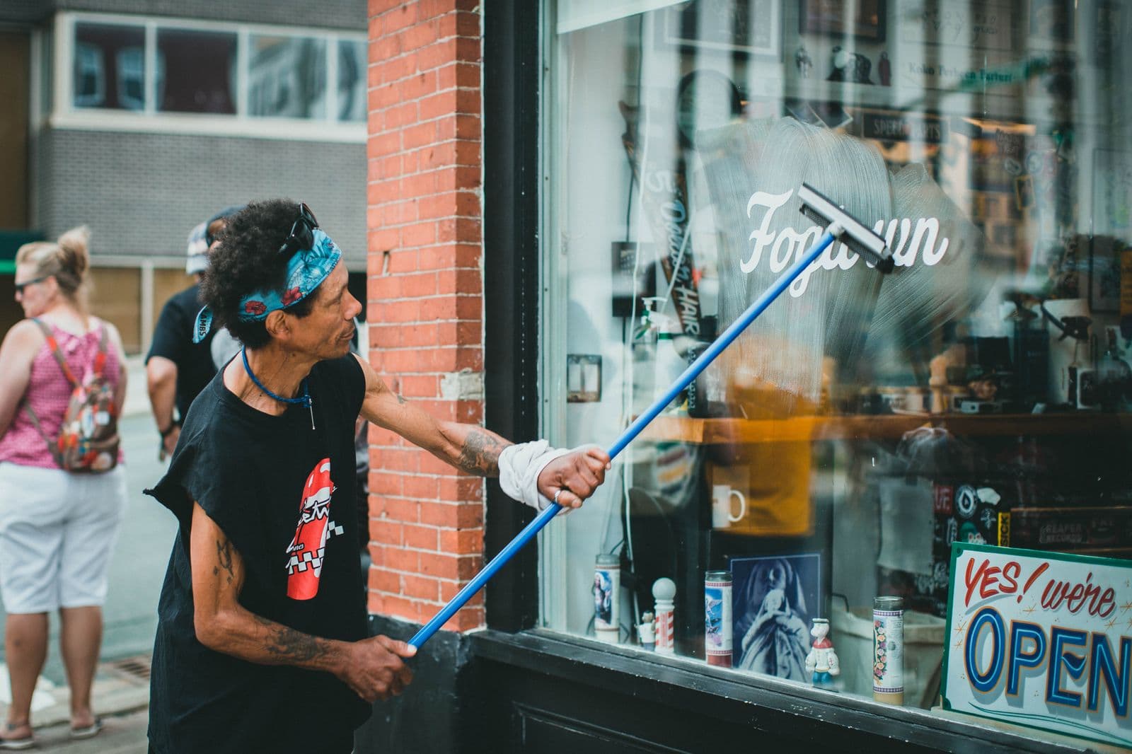 Trabajador limpiando la vidriera de un local comercial con squeegee profesional