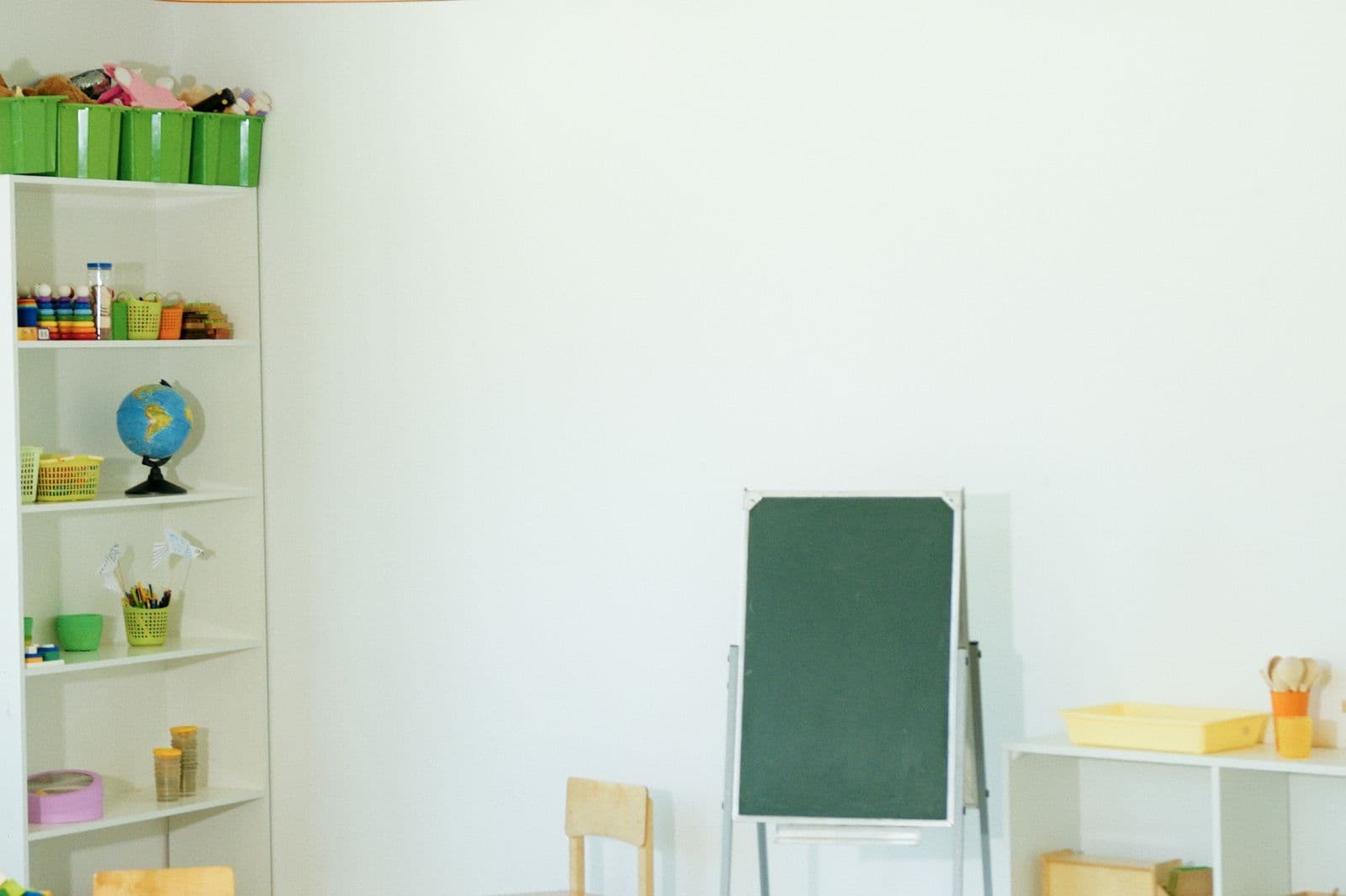 Aula infantil luminosa con juguetes, globo terráqueo y pizarra escolar