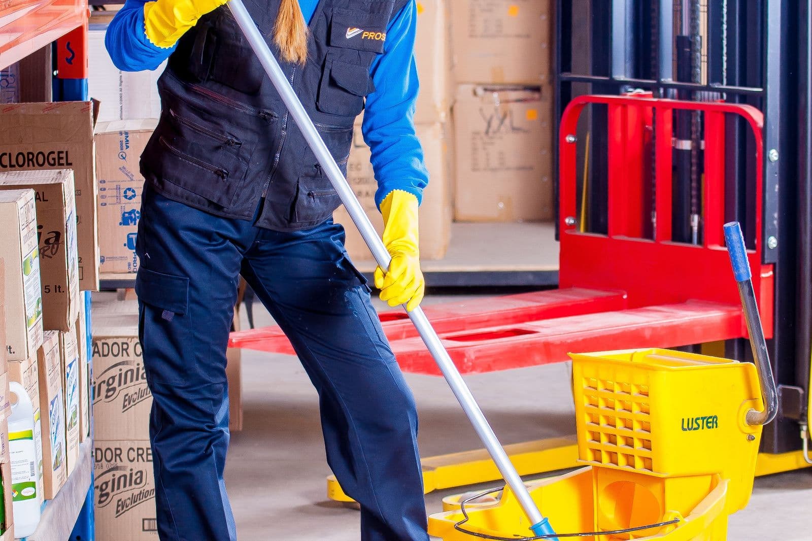 Personal de limpieza con uniforme completo trabajando en un depósito industrial