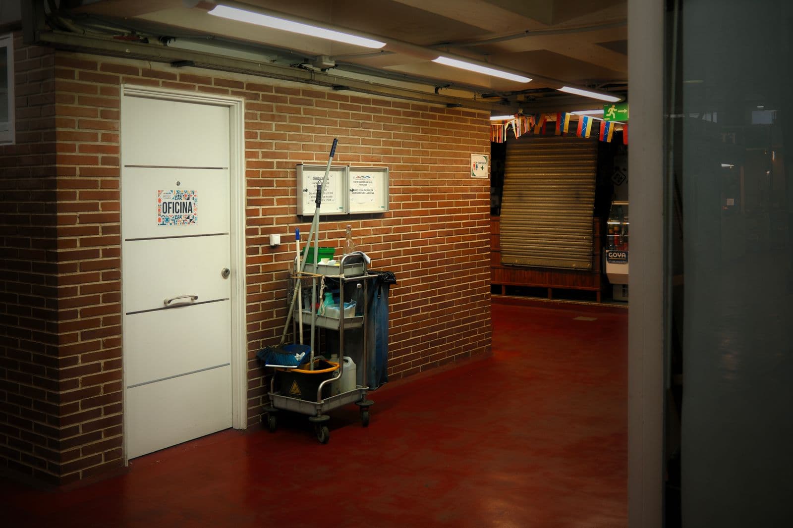Carrito de mantenimiento periódico junto a puerta de oficina en un pasillo comercial